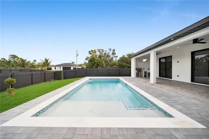 View of swimming pool with a patio area, a ceiling fan, a fenced backyard, and exterior kitchen