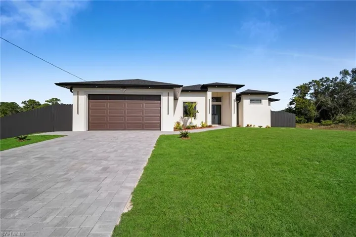 Prairie-style home featuring decorative driveway, stucco siding, and a garage