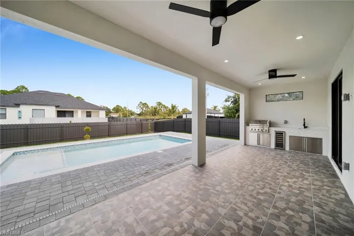 View of swimming pool with an outdoor kitchen, a patio area, a fenced backyard, and a ceiling fan
