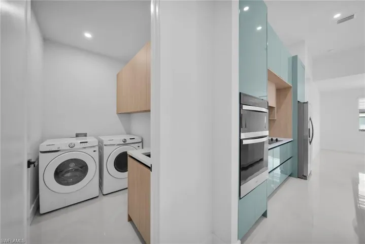 Laundry room featuring cabinet space, washing machine and dryer, recessed lighting, and finished concrete floors
