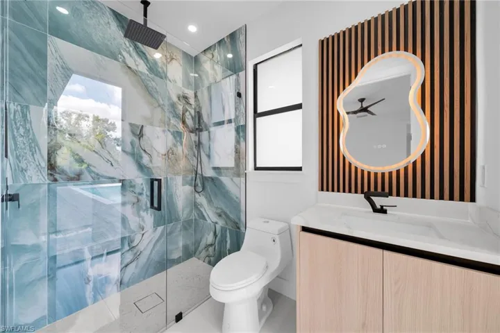 Bathroom featuring a marble finish shower and vanity