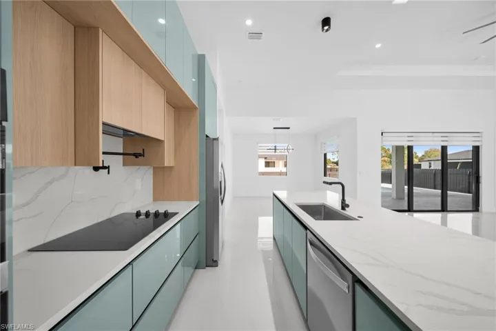 Kitchen with modern cabinets, light stone countertops, appliances with stainless steel finishes, recessed lighting, and pendant lighting