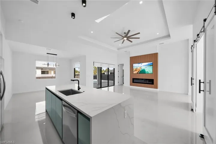 Kitchen featuring modern cabinets, a barn door, light stone counters, pendant lighting, and open floor plan