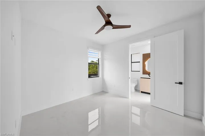 Unfurnished bedroom featuring ceiling fan, concrete flooring, and connected bathroom