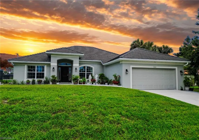 Single story home featuring stucco siding, a lawn, an attached garage, and concrete driveway