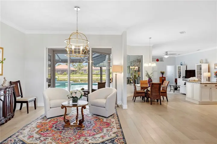Living room with ceiling fan with notable chandelier, light hardwood / wood-style flooring, and ornamental molding