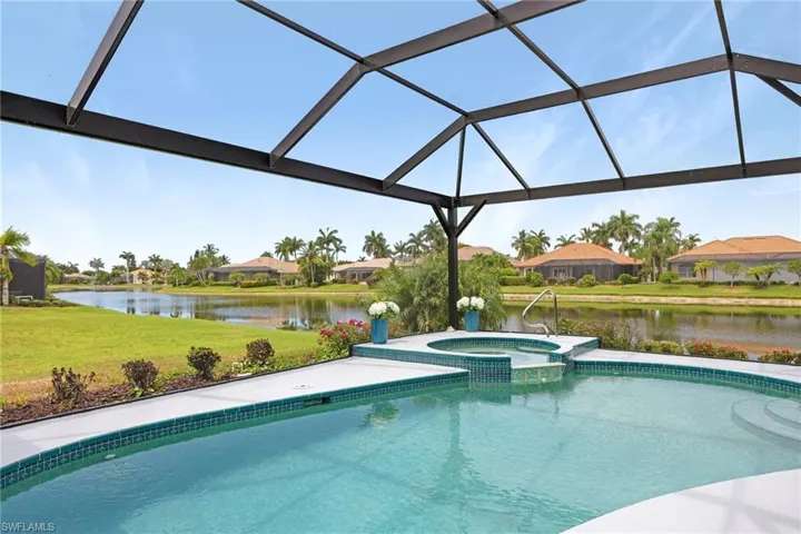 View of pool featuring glass enclosure, an in ground hot tub, and a yard