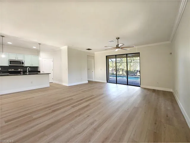 Unfurnished living room with crown molding, light wood-style flooring, and ceiling fan