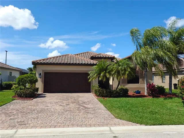 Mediterranean / spanish house with a front lawn, stucco siding, a garage, and decorative driveway