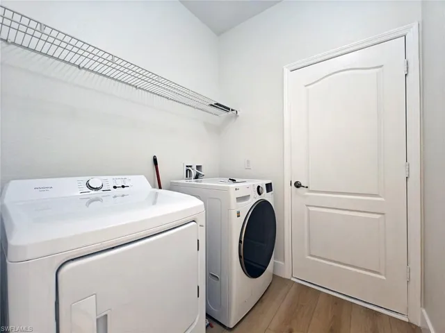 Laundry area with wood finished floors and independent washer and dryer