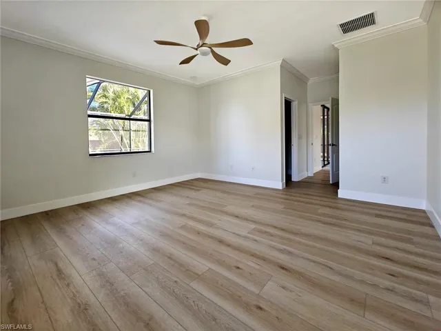 Primary bedroom featuring ornamental molding, light wood-type flooring, and a ceiling fan