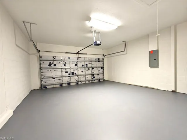 Garage with concrete block wall, electric panel, and a garage door opener