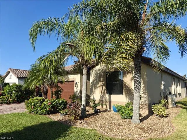 View of front of house featuring stucco siding, a garage, a front lawn, and a tile roof
