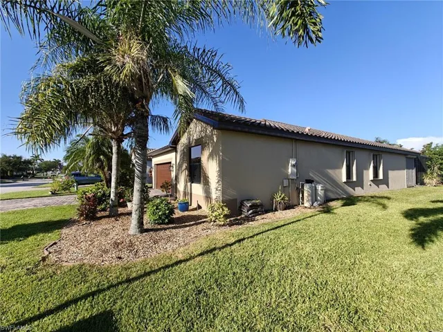 View of property exterior with a yard, stucco siding, an attached garage, and a tile roof