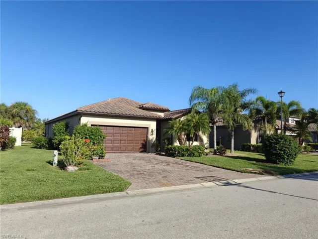 View of front of property with stucco siding, a front lawn, decorative driveway, and an attached garage