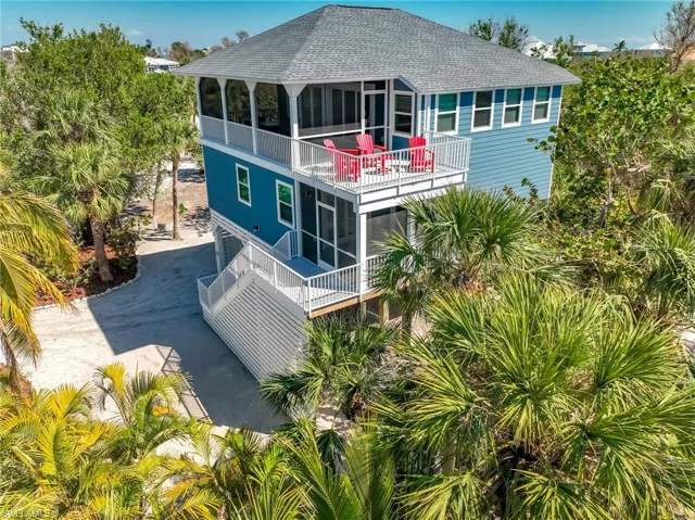Back of house featuring a sunroom, roof with shingles, driveway, and a balcony