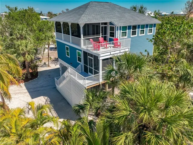 Back of property featuring driveway, a sunroom, a balcony, and roof with shingles