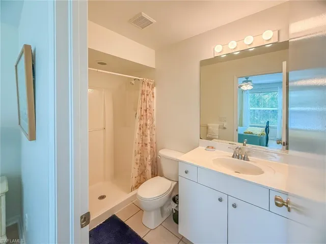 Ensuite bathroom with visible vents, toilet, a stall shower, vanity, and tile patterned floors