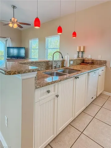 Kitchen featuring a peninsula, plenty of natural light, white dishwasher, and a sink