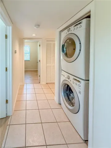 Laundry area featuring light tile patterned floors, baseboards, laundry area, and stacked washer and clothes dryer