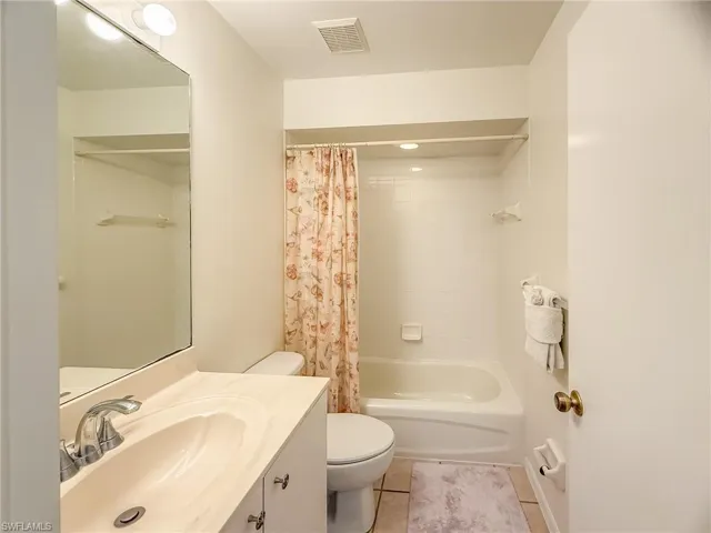 Bathroom with visible vents, toilet, tile patterned flooring, shower / bath combo with shower curtain, and vanity