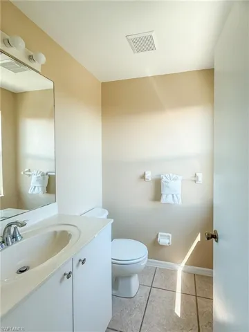 Bathroom with toilet, vanity, tile patterned flooring, and visible vents