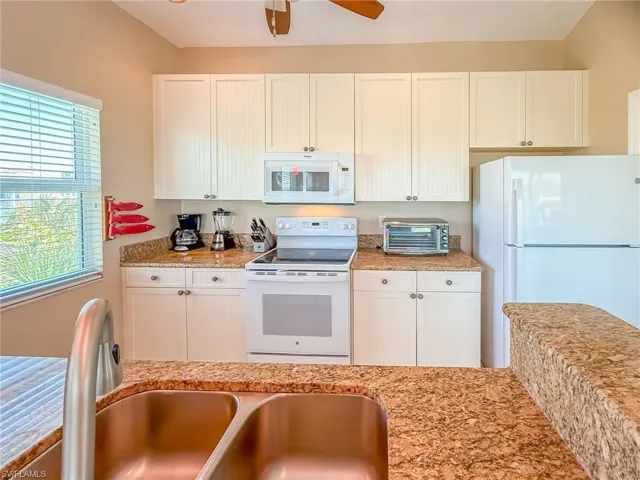 Kitchen featuring a toaster, white appliances, a sink, a ceiling fan, and white cabinetry