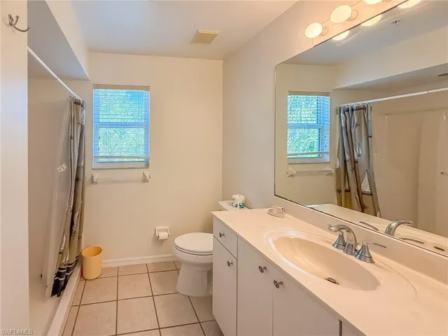 Bathroom with toilet, vanity, baseboards, visible vents, and tile patterned floors