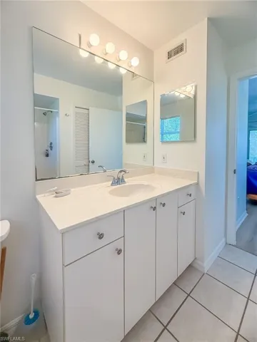 Bathroom with vanity, tile patterned flooring, visible vents, and baseboards