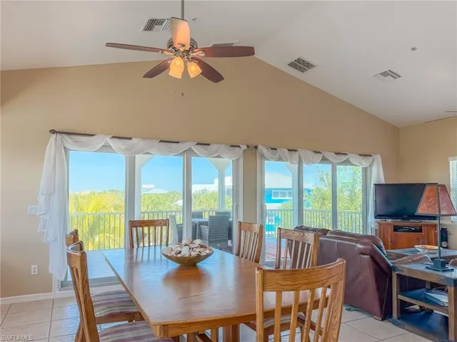 Dining area featuring ceiling fan, visible vents, vaulted ceiling, and light tile patterned floors