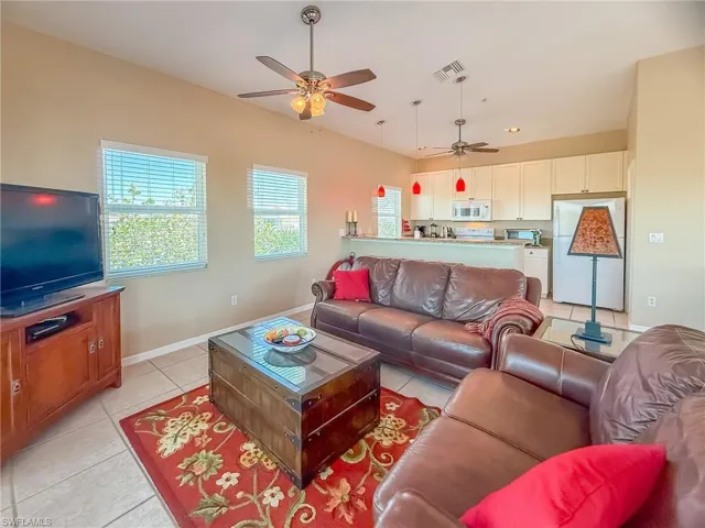 Living room featuring a ceiling fan, visible vents, baseboards, and light tile patterned floors