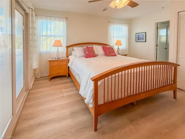 Bedroom with light wood-type flooring, multiple windows, and a ceiling fan