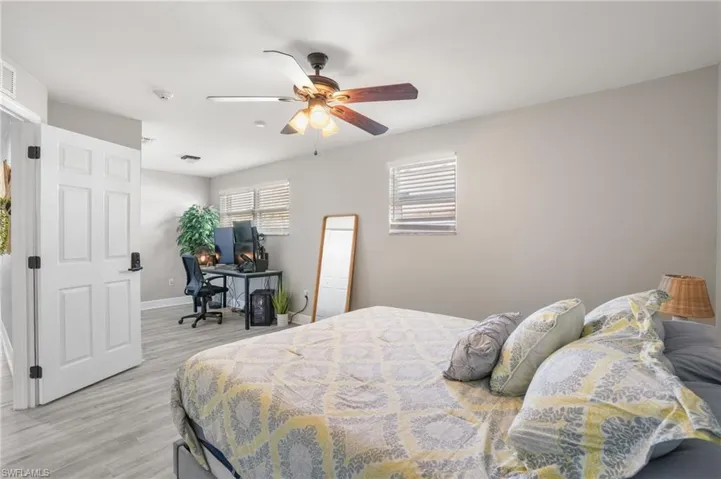Bedroom featuring light wood-style floors, ceiling fan, and a desk