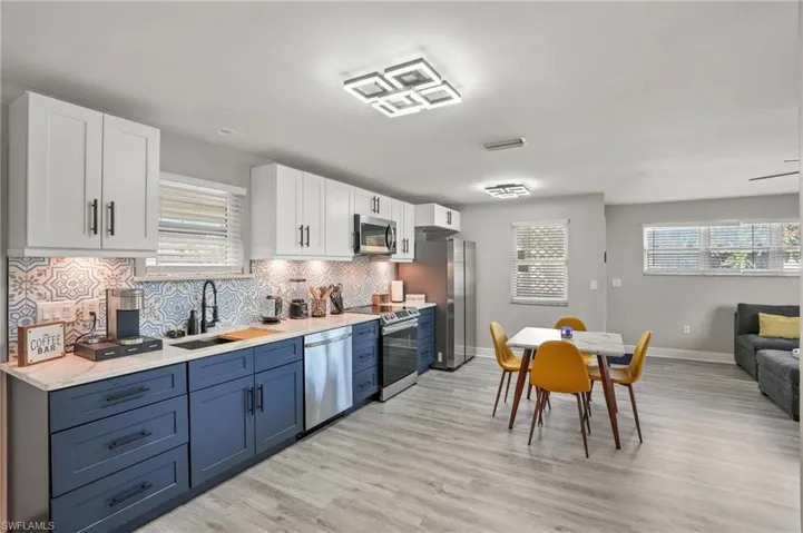 Kitchen featuring appliances with stainless steel finishes, light countertops, white cabinets, and light wood-style flooring