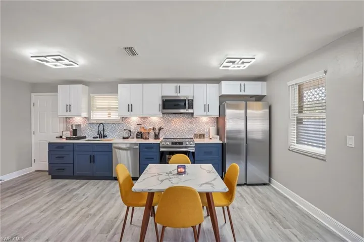 Kitchen featuring stainless steel appliances, blue cabinets, backsplash, and light wood finished floors