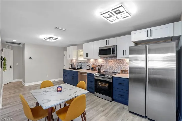 Kitchen with appliances with stainless steel finishes, blue cabinets, backsplash, light countertops, and recessed lighting