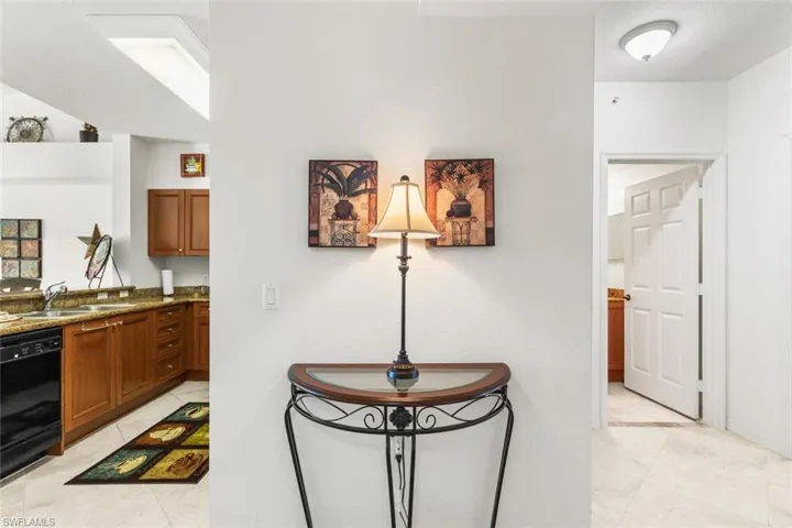 Kitchen featuring dishwasher, light stone counters, and sink
