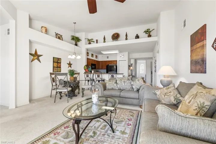 Living room featuring ceiling fan with notable chandelier and light colored carpet