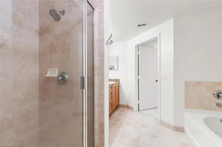 Bathroom with tile patterned flooring, vanity, and shower with separate bathtub