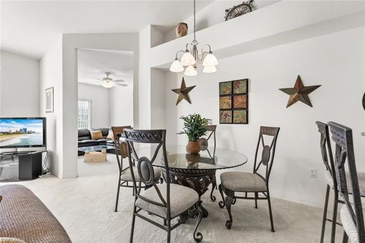 Dining area featuring carpet and ceiling fan with notable chandelier