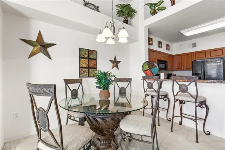 Dining space with light carpet and a chandelier