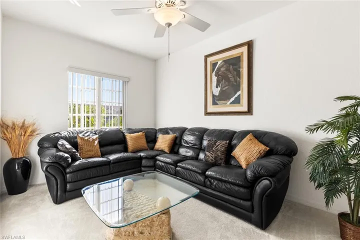Carpeted living room featuring ceiling fan