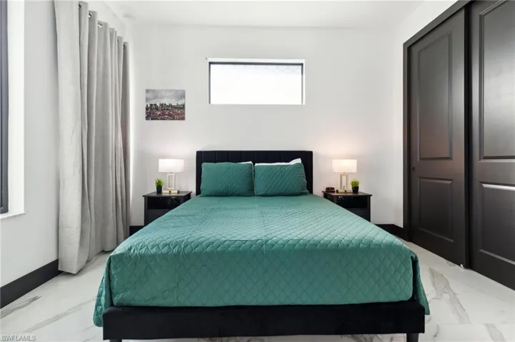 Bedroom with marble look tile flooring and a closet