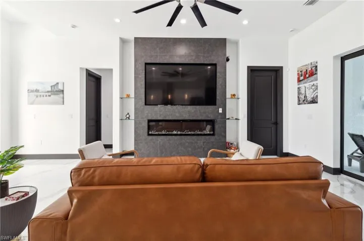 Living room with light marble finish floors, a tile fireplace, recessed lighting, and a ceiling fan