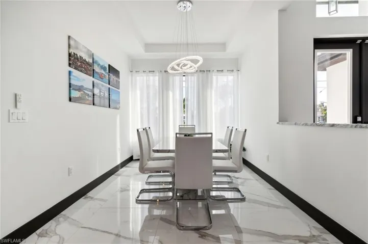 Dining area featuring plenty of natural light, light marble finish floors, and a tray ceiling