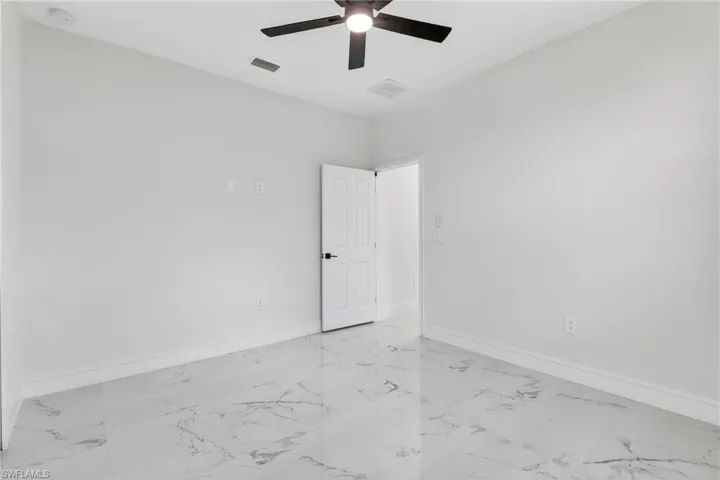 Empty room featuring light marble finish floors and a ceiling fan