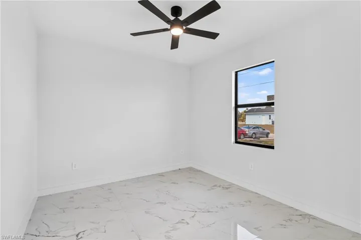 Empty room featuring light marble finish floors and a ceiling fan