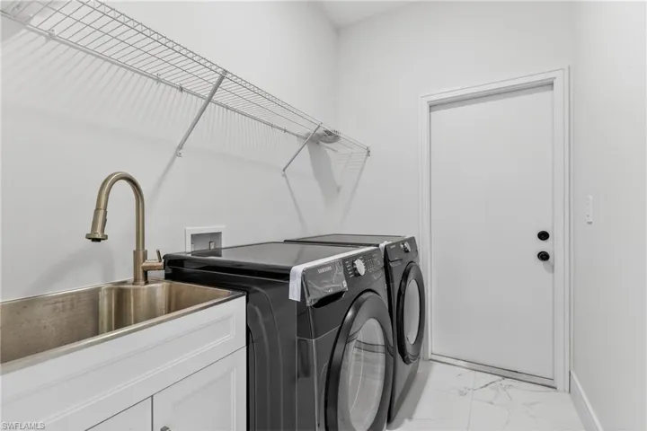 Laundry room featuring light marble finish floors and washing machine and dryer