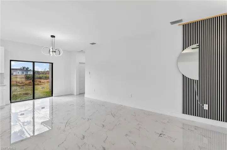 Spare room with hanging lights and light marble finish floors