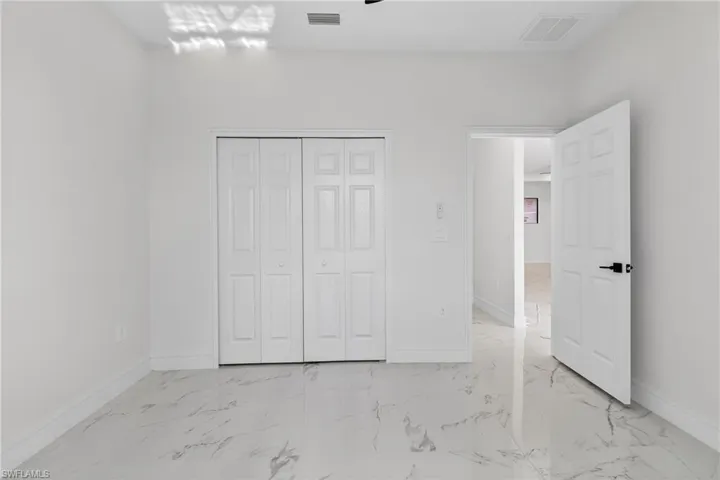Unfurnished bedroom with light marble finish flooring and a closet